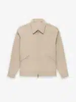 A Fear of God Taupe Zip Denim Jacket 'Dusty Beige', featuring long sleeves, a pointed collar, and two diagonal front pockets, displayed on a plain white background.