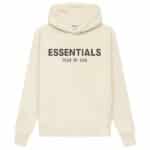 The Fear of God Essentials Oversized Hoodie 'Butter-Cream' showcases a cream-colored design with bold black ESSENTIALS text and FEAR OF GOD subtly printed beneath it. It includes a front pocket and a drawstring hood.