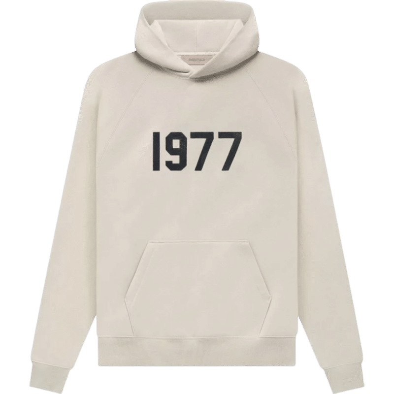 The Fear of God 1977 Essentials Hoodie 'Wheat' is a cream-colored hoodie featuring a bold black "1977" printed on the chest. It includes a front kangaroo pocket and a hood, crafted from soft material, and is displayed on a plain green background.