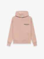 A 'Pink' hoodie from Fear of God Essentials features a front pocket and hood. The chest showcases the text ESSENTIALS Fear of God in black print, set against a plain white background.