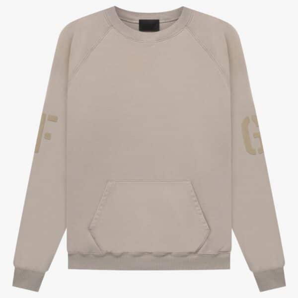 Introducing the FG Essentials Crewneck Sweatshirt 'Core-Heather', a soft and comfortable beige sweatshirt. It boasts a minimalistic design with long sleeves, a large front pocket, and subtle lettering on the sleeves.