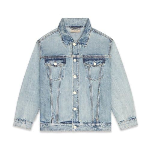 The Fear of God Essentials Denim Jacket features a classic collar, silver buttons down the front, and two chest pockets with flap and button closures. It is crafted from light blue denim with a slightly faded appearance.