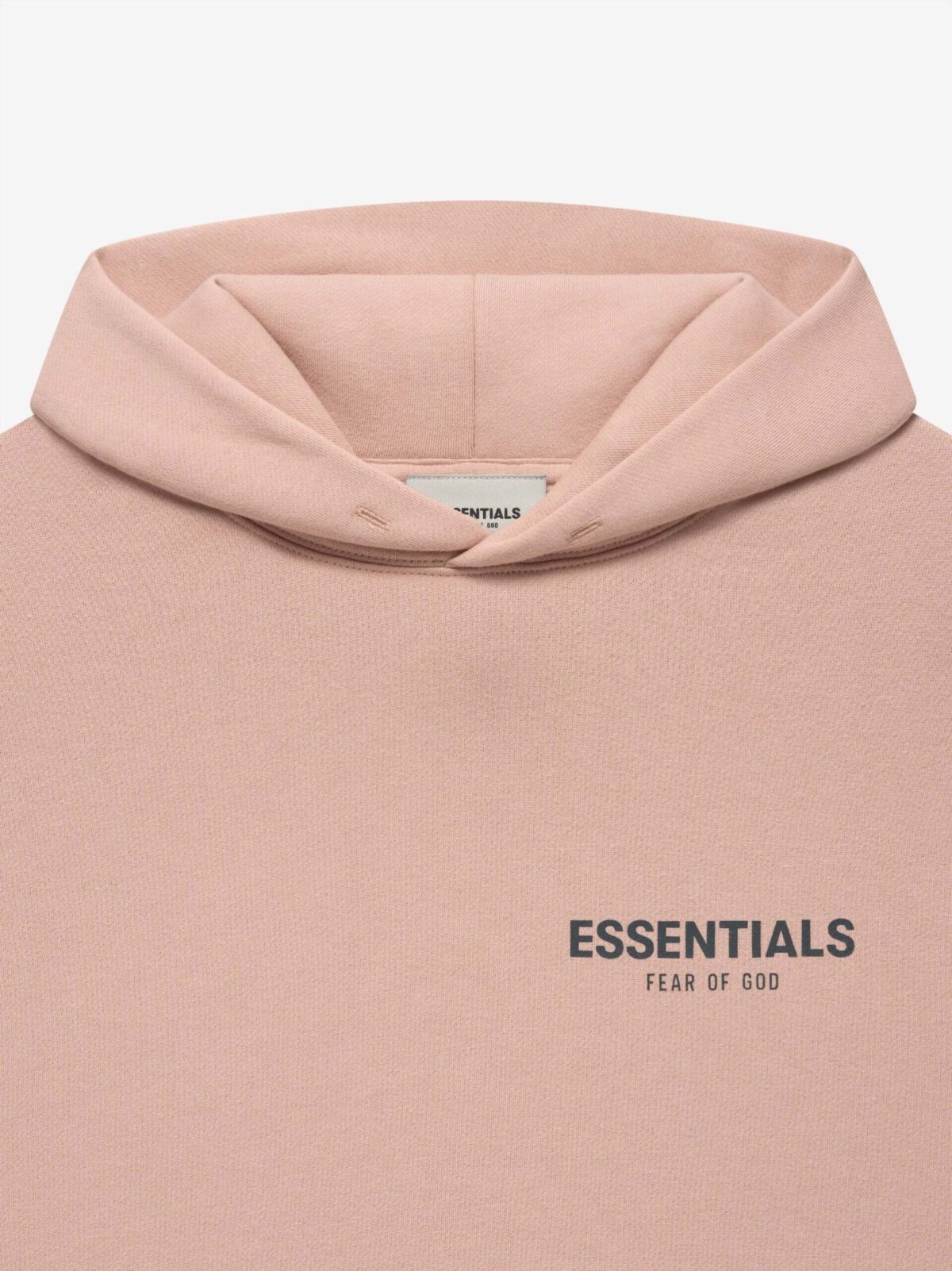 Close-up of a light pink hoodie featuring the words "FEAR OF GOD ESSENTIALS" printed prominently in dark letters on the front. The design is minimalist, showcasing a clean look with a noticeable hood at the top.