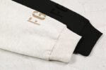 Close-up of two sweatshirt sleeves laid side by side on a marble surface. One sleeve is light oatmeal with FG7C printed in tan, and the other is black with FG printed in black. Each sleeve has ribbed cuffs.